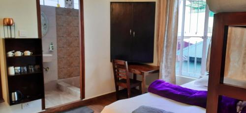 a bedroom with a bed and a television and a desk at A La Maison in Shillong