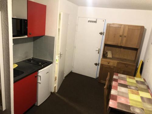 une petite cuisine avec des placards rouges et une table dans l'établissement Résidence Cimes De Caron - Studio pour 4 Personnes MAE-7984, à Val Thorens