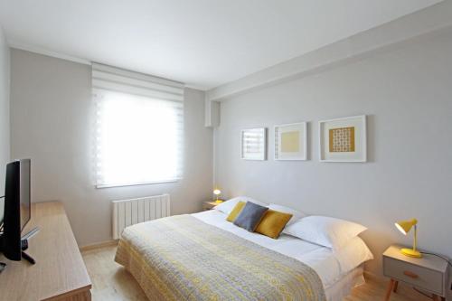 une chambre blanche avec un lit et une télévision dans l'établissement Bel appartement sur la plage, à Grimaud