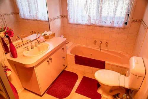 a bathroom with a tub and a toilet and a sink at Ballarat Aroma Cottage in Ballarat