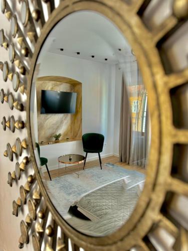 Un espejo que refleja una habitación con una silla y un sofá. en Blancris Boutique, en Brasov