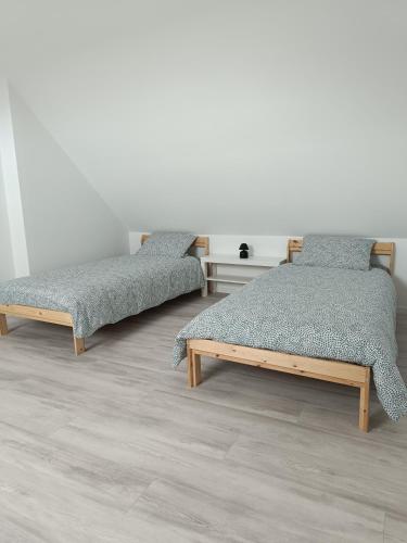 deux lits côte à côte dans une pièce dans l'établissement L'eau de la, à Saint-Côme-de-Fresné