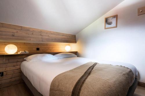 une chambre avec un grand lit avec un mur en bois dans l'établissement Chalet Mouflon - 3 Pièces pour 4 Personnes MAE-1931, à Val Thorens