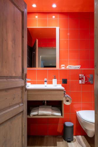La salle de bains orange est pourvue d'un lavabo et d'un miroir. dans l'établissement Chalet Mouflon - 3 Pièces pour 4 Personnes MAE-1931, à Val Thorens