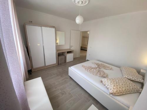 a small white bedroom with a bed and a mirror at Best Summer Apartment in Golem