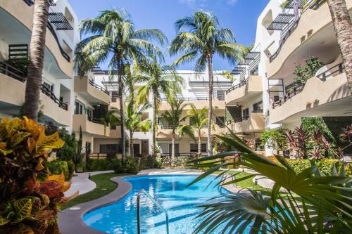 an apartment complex with a swimming pool and palm trees at Creuza de Mä in Playa del Carmen