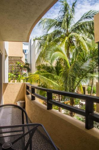 a balcony with a chair and a palm tree at Creuza de Mä in Playa del Carmen