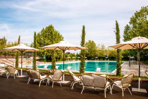 eine Gruppe von Stühlen und Sonnenschirmen neben einem Pool in der Unterkunft Living Place Hotel in Villanova