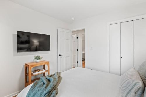 a white bedroom with a bed and a tv on a wall at 1 5 Miles to Mizzou ~ Spacious & Updated Home~ in Columbia