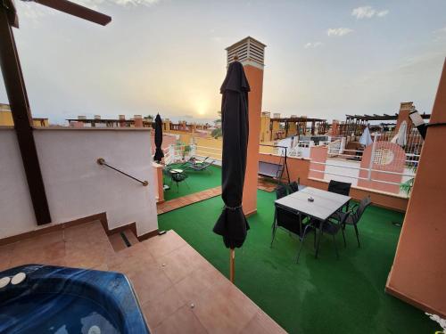 eine Terrasse mit einem Tisch und einem Sonnenschirm auf dem Dach in der Unterkunft Laguna Beach Relax - Terraza, Jacuzzi, Parking in Vera