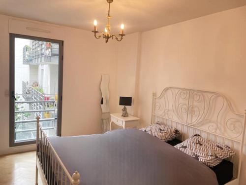 - une chambre avec un lit, un lustre et une fenêtre dans l'établissement Beautiful and large apartment Paris Montparnasse, à Paris