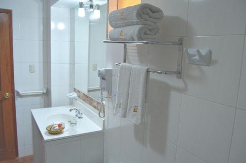 een badkamer met een wastafel, een spiegel en handdoeken bij Siete Ventanas in Cuzco