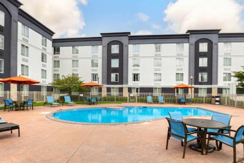 a swimming pool with tables and chairs and a building at Best Western Premier Richmond City Gateway in Richmond