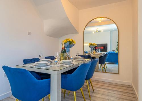 a dining room with a table and blue chairs and a mirror at The Hive in Coventry
