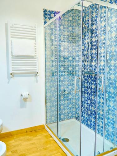 a bathroom with a shower with blue and white tiles at Qurchiti in Capo dʼOrlando