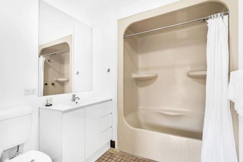 a white bathroom with a shower and a toilet at Coastal Retreat with Marina & Ocean Views in Nelson Bay