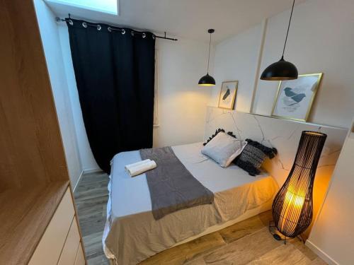 - une chambre avec un lit doté d'un rideau noir et d'une guitare dans l'établissement Le Duo Cosy Parking, à Carcassonne