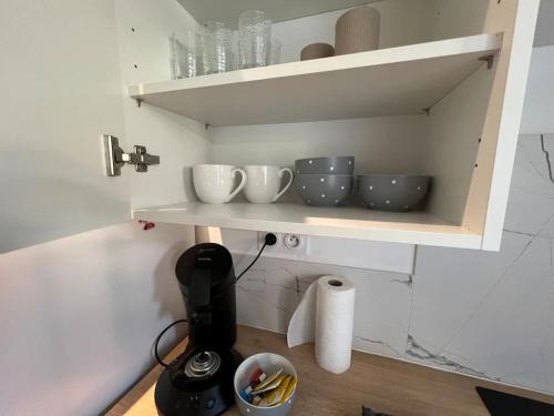 une étagère avec des bols et des tasses dans une cuisine dans l'établissement Le Duo Cosy Parking, à Carcassonne