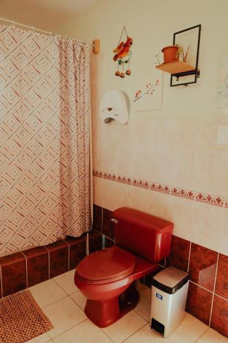 a bathroom with a red toilet and a shower at Kinti Wasi Casa de Campo Hospedaje in Los Baños del Inca