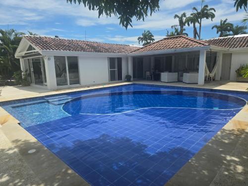 a blue swimming pool in front of a house at Hermosa casa en condominio campestre el peñon in Girardot