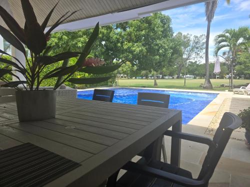 a table and chairs with a potted plant next to a pool at Hermosa casa en condominio campestre el peñon in Girardot