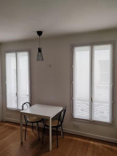 une table et des chaises dans une pièce avec des fenêtres dans l'établissement Studio moderno al centro di Parigi - République, à Paris