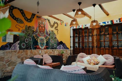 a room with chairs and a wall with a mural at Kinti Wasi Casa de Campo Hospedaje in Los Baños del Inca