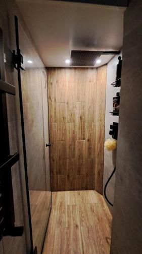 a bathroom with a shower with a wooden wall at Cherry Apartments- CHILL in Wałbrzych