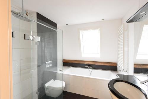a bathroom with a tub and a toilet and a sink at Spacious and attractive family home near Amsterdam in Overveen