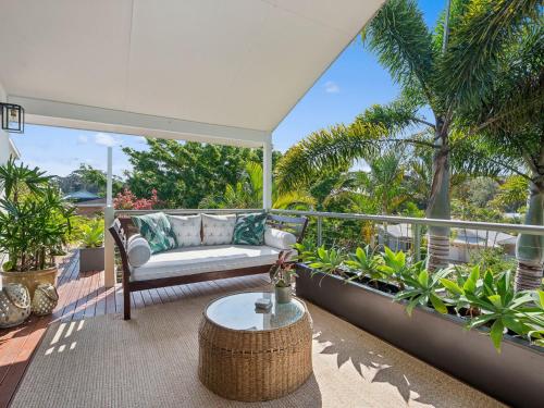 a patio with a couch and a table on a balcony at Woolgoolga Lake House in Woolgoolga