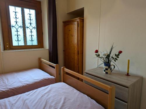 a bedroom with two beds and a window with flowers on a table at Gîte charmant en Sologne : balades, pêche, visites de châteaux, animaux bienvenus - FR-1-590-100 in Villemurlin