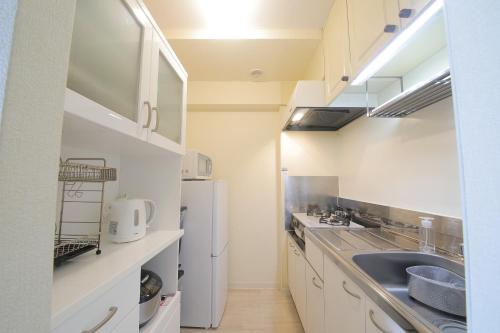 a kitchen with a sink and a refrigerator at ノーザンヒルズ南6条 in Sapporo