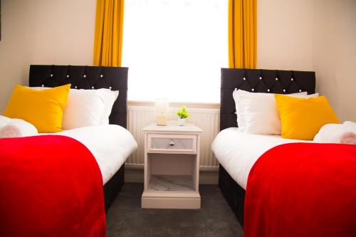 two beds in a room with red and yellow pillows at Lucky Home 24 - Ideal for Trade & Family - 2 Bedrooms - 3 Beds - Max 4 Guests - Close to BAE, Docks, Lake District, Beaches in Barrow in Furness