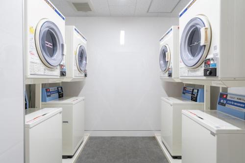 a white laundry room with four washers and dryers at BON Condo Namba Nipponbashi in Osaka
