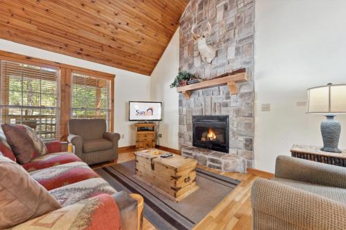 a living room with a stone fireplace at Mayberry Lodge Cabin in Branson West
