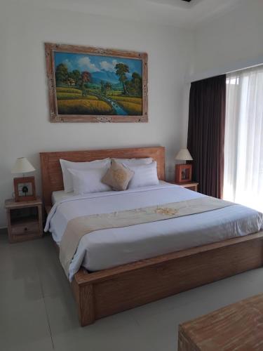 a bedroom with a large bed with a painting on the wall at Sujiwa Ubud Hotel & Villa in Ubud