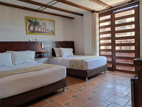 a hotel room with two beds and a window at La Floresta de Cite Hotel in Cite