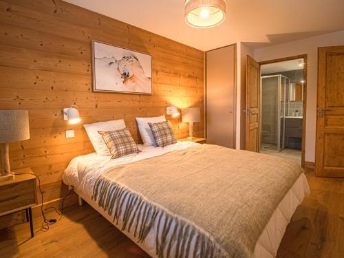 une chambre avec un lit et un mur en bois dans l'établissement Appartement cosy 7 pers, 2 chambres, pied de pistes avec parking et WiFi - FR-1-356-517, à Valmorel