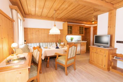 a kitchen and dining room with a table and a television at Ferienwohnungen Hörmann in Hirschegg
