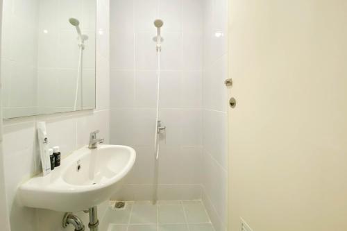 ein weißes Badezimmer mit Waschbecken und Dusche in der Unterkunft Studio Furnished with Comfort Design at Tokyo Riverside PIK 2 Apartment By Travelio in Rawalembang