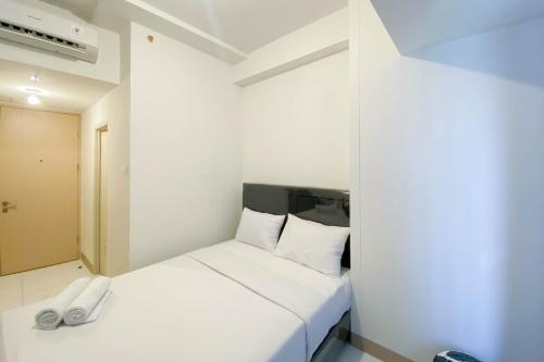 ein Schlafzimmer mit einem weißen Bett in einem Zimmer in der Unterkunft Studio Furnished with Comfort Design at Tokyo Riverside PIK 2 Apartment By Travelio in Rawalembang