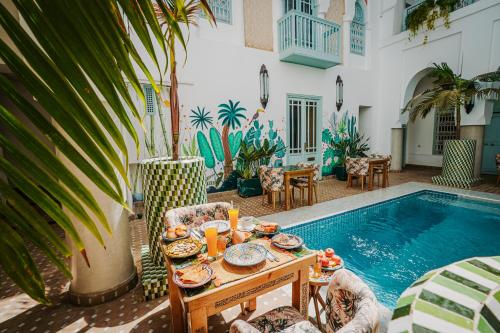 - une table avec des assiettes de nourriture à côté de la piscine dans l'établissement Riad Assouel et Spa By La Siredrah, à Marrakech