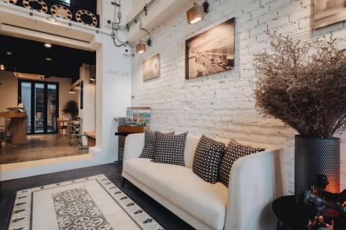 a living room with a couch and a brick wall at Xinlor House - Phuket Old Town in Phuket Town