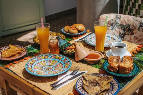 une table avec des assiettes de nourriture et des verres de jus d'orange dans l'établissement Riad Assouel et Spa By La Siredrah, à Marrakech