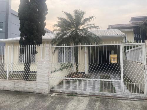 a white fence in front of a house at Suíte privativa com cama Queen em casa ampla e confortável em casa compartilhada in Palhoça
