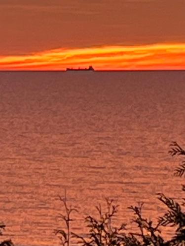 a sunset over the ocean with a ship in the distance at Drift in Goderich