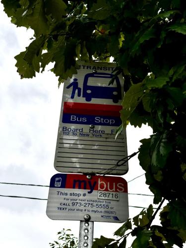 a bus stop sign on a pole with signs at Private 1st floor Apartment - Only 5 min Away from Newark Airport and 30 min to NYC in Elizabeth