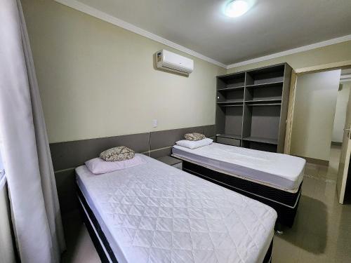 2 Betten in einem kleinen Zimmer mit Spiegel in der Unterkunft Acrópole Residence in Bombinhas