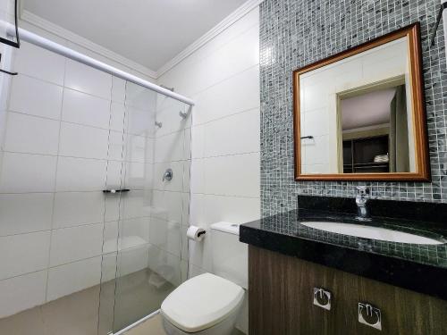 ein Badezimmer mit Toilette, Waschbecken und Spiegel in der Unterkunft Acrópole Residence in Bombinhas