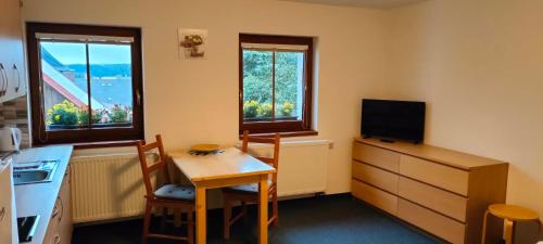 a kitchen with a table and a small table and two windows at Apartmány Na náměstí in Boží Dar